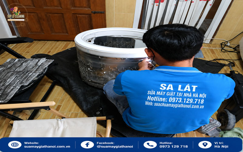 Thợ sửa máy giặt đang kiểm tra linh kiện bên trong máy giặt tại nhà khách hàng