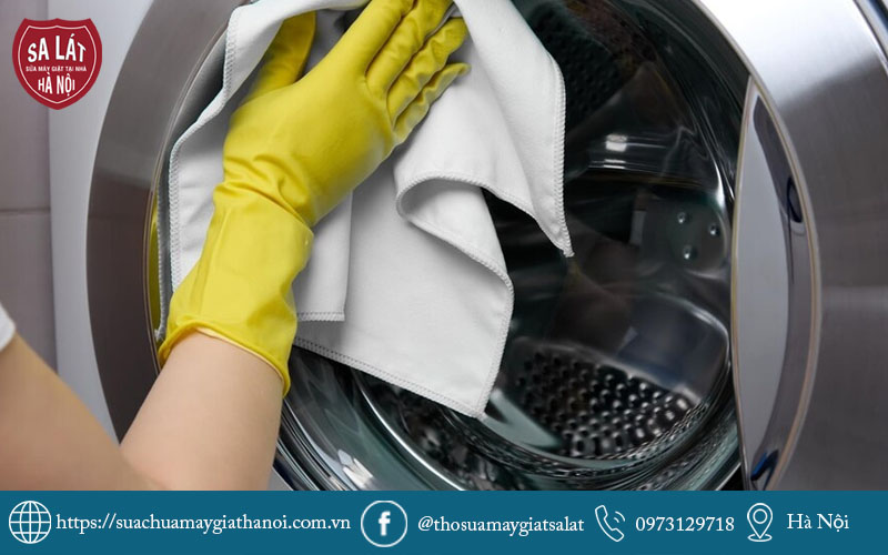Thợ kỹ thuật đang tận tâm lau chùi, vệ sinh sạch sẽ bên trong lồng máy giặt cửa ngang